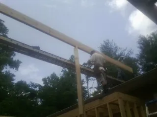 Carpenter setting a ridge beam over a new addition frame — Ice Dam Removal by Roofing Brothers in Milliken