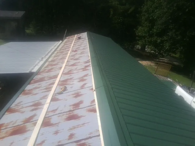 Old rusted panels beside newly installed green metal roofing — Wind Damage Roof Repair by Roofing Brothers in Milliken