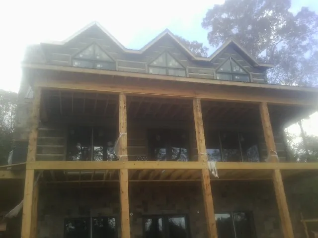 Dormers and porch framing on a large log home under construction — Roof Coating work by our crew in Milliken