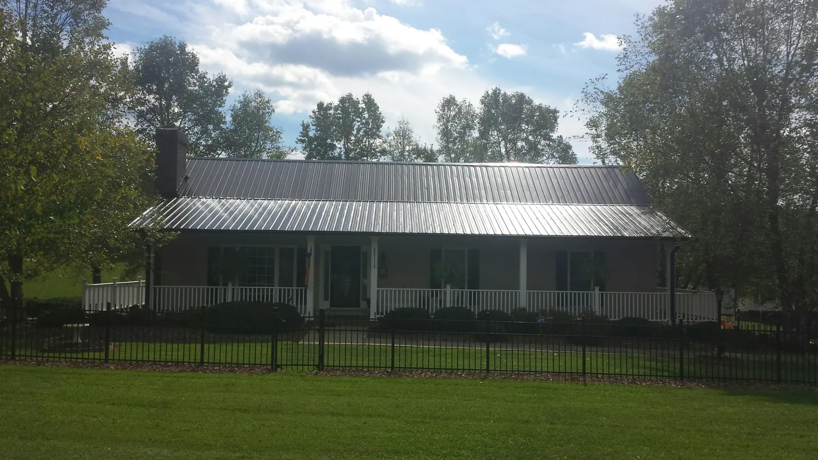 Gray metal roof on a brick ranch with a full width front porch — Gutter Guard Installation work by our crew in Milliken