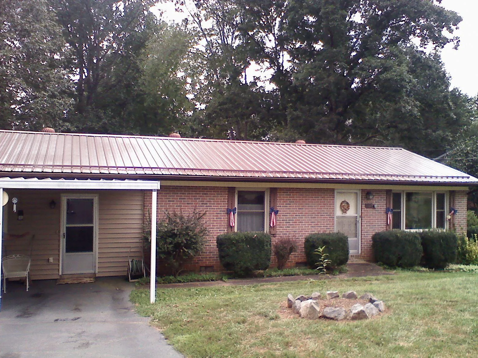 Bronze metal roof and carport on a brick ranch home — Roof Repair work by our crew in Milliken