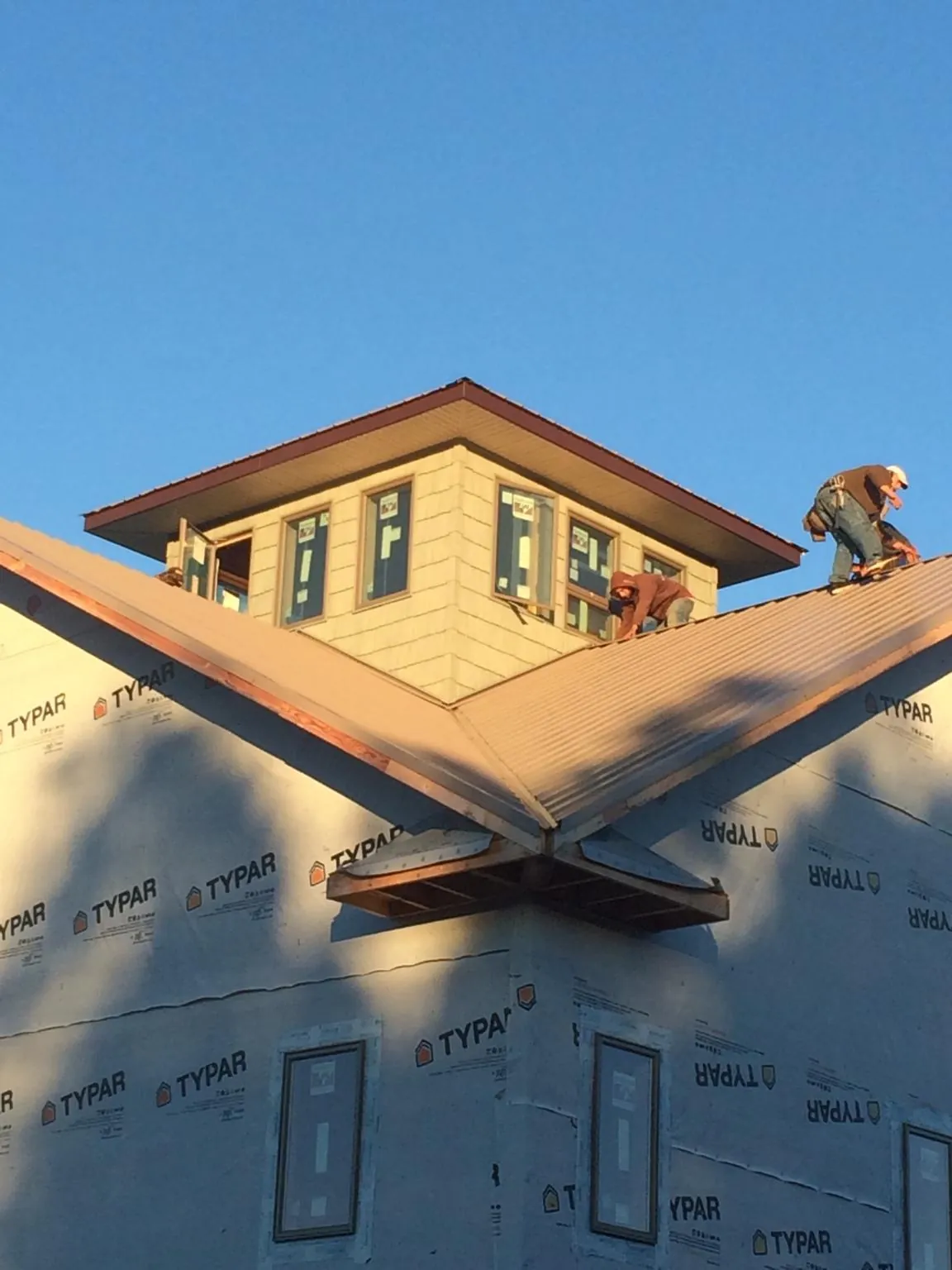 Roofers working around a rooftop cupola on a new metal roof at sunset — Roof Waterproofing in Milliken by Roofing Brothers